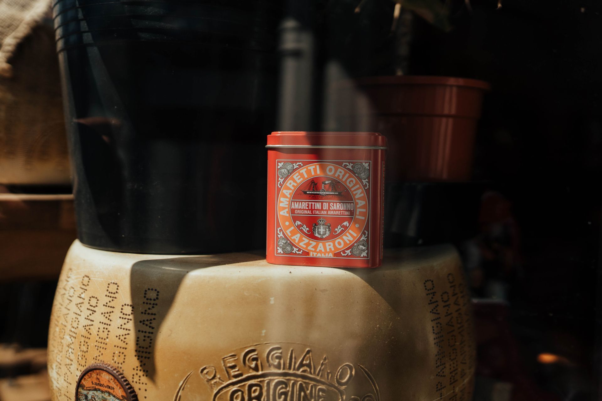 an amaretti tin displayed on wheels of Parmesan cheese